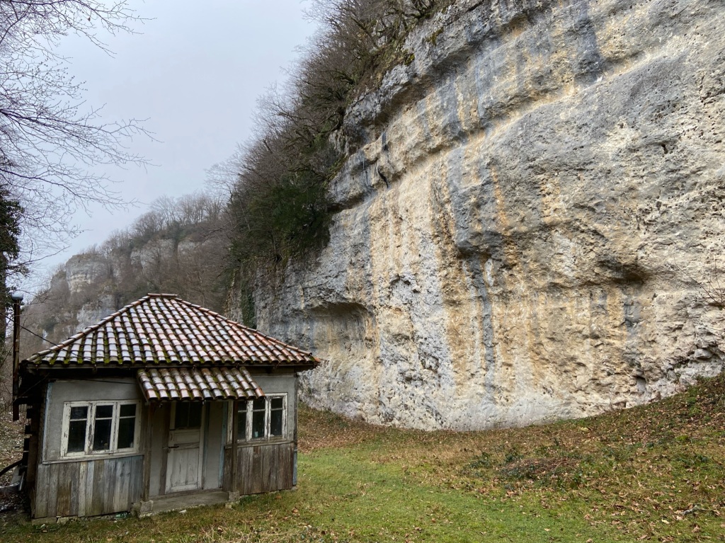 The large limestone crag of sector canyon. At the bottom of the canyon there is a small wooden hut with a tiled roof