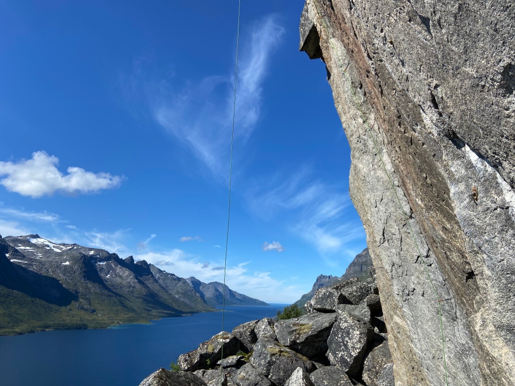 Steep overhanging granite rock at Ersfjorden with the rope hanging down which highlights how steep it is! Below there is a fjord which has more rocky mountains on the other side
